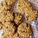 A cookie drying rack with oatmeal raisin cranberry cookies layered on top.