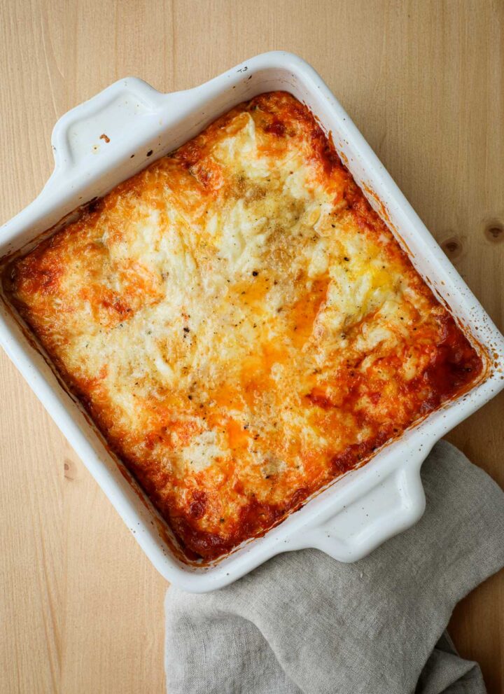 Eggs baked in tomato sauce topped with fontina and breadcrumbs in a casserole dish.