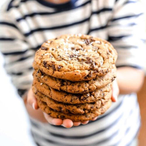 Child holding a stack of large Chocolate Chip Cafe Cookies.
