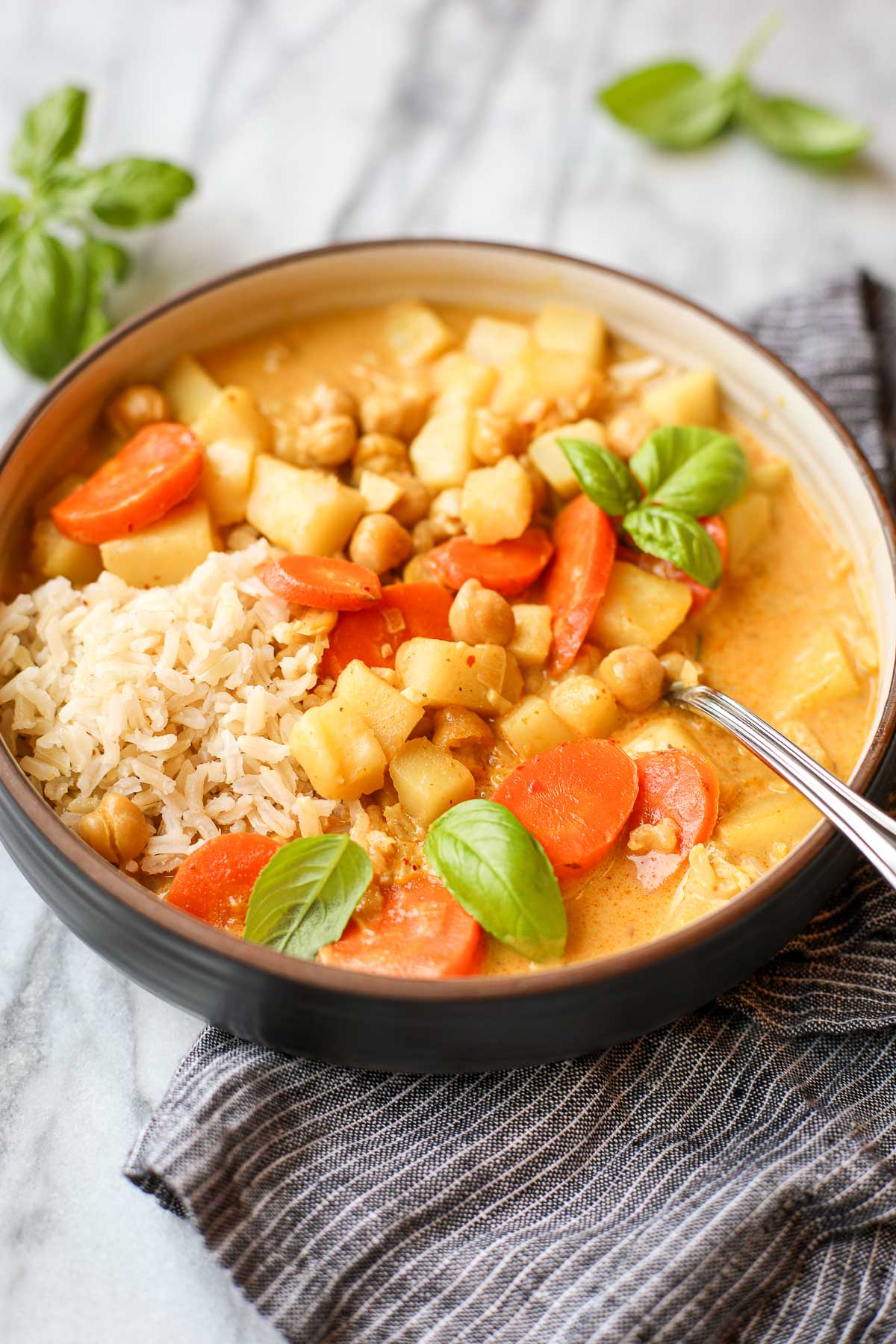 Yellow Thai Curry in a bowl with brown rice, potatoes, carrots and chickpeas.