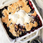 Swedish Blueberry Pie in a square baking dish with melted vanilla ice cream on top.