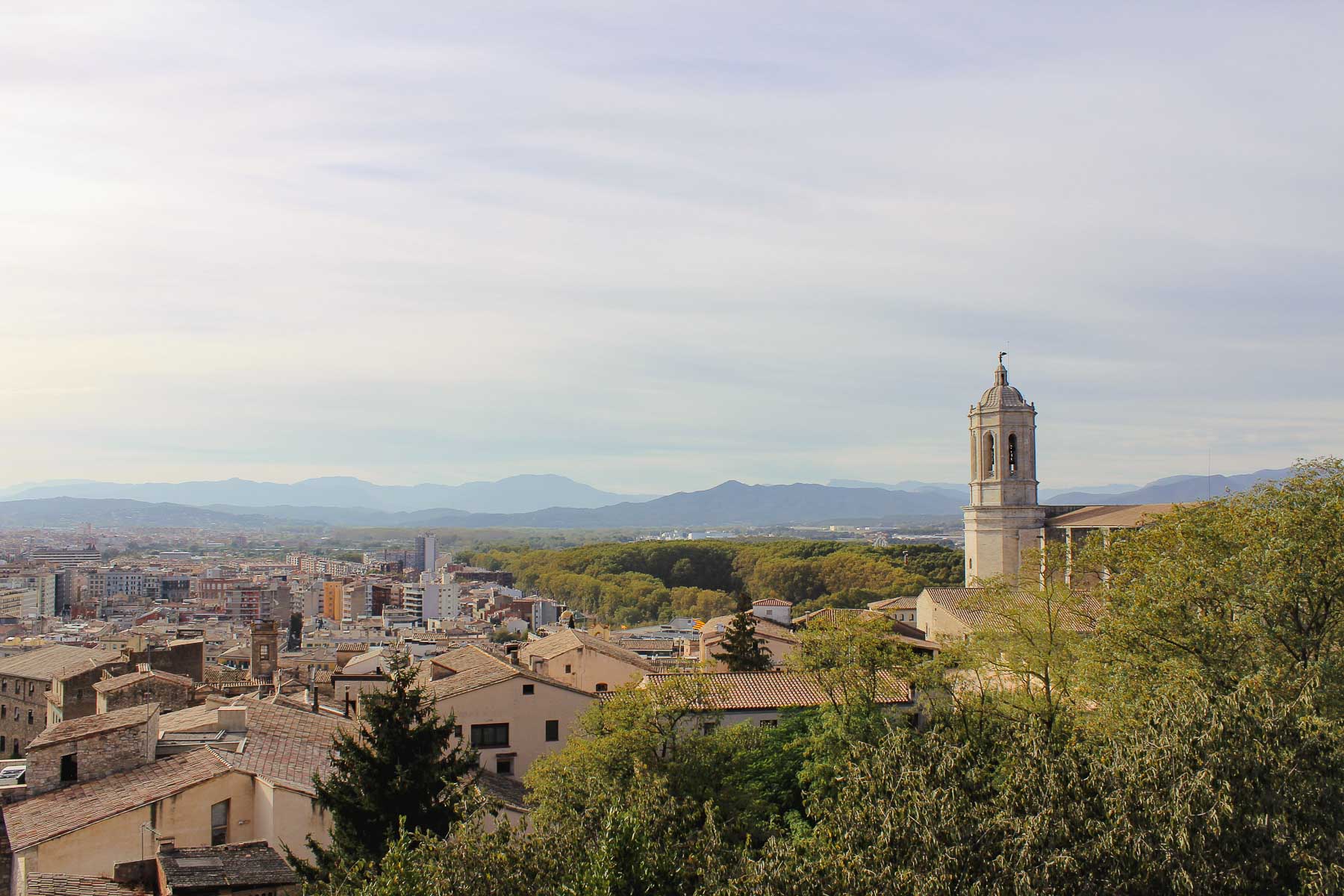 A view of the city of Girona from up on a hill where a restaurant in the city sells Roman style pizza.
