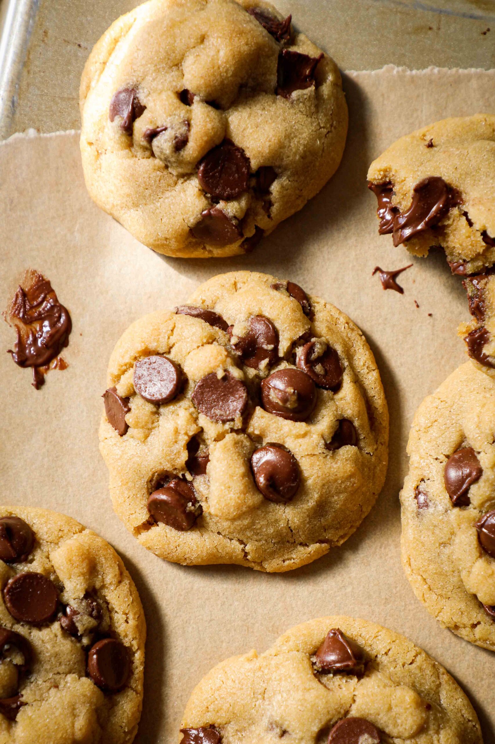 A melty chocolate chip cookie on a gold cookie sheet.