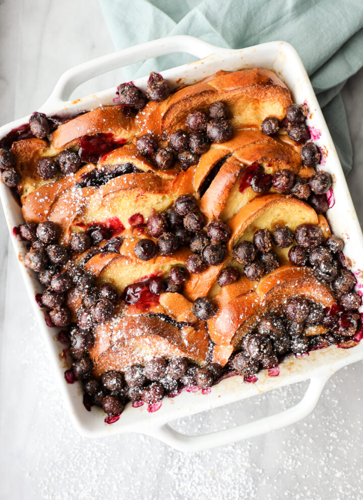 Overhead shot of a blueberry french toast casserole with fresh blueberries and powdered sugar.