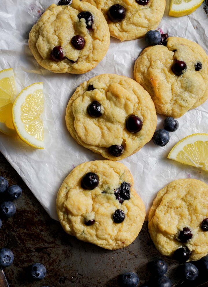 Lemon Blueberry Cookies on an aged sheet pan with fresh blueberries and lemon slices.