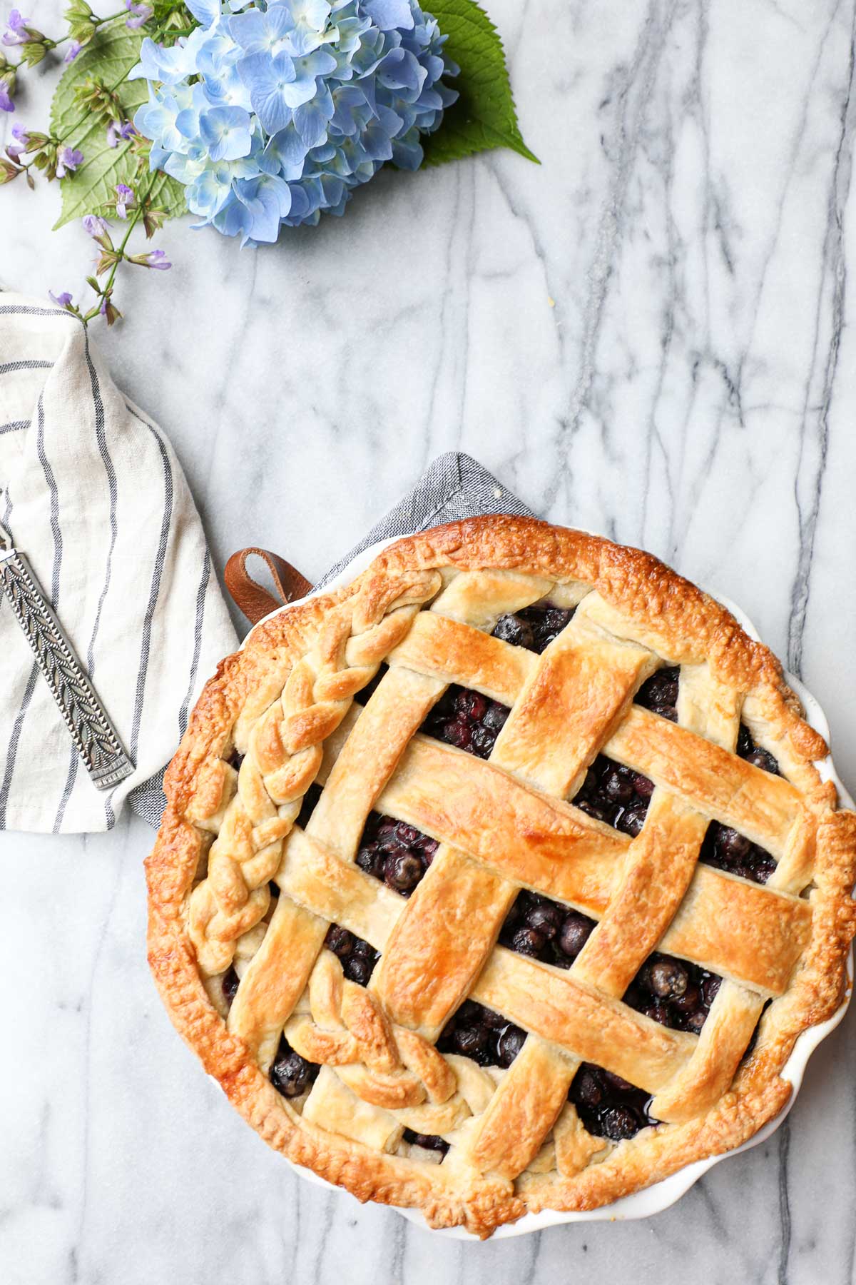 Classic Blueberry Pie with a golden brown lattice top partially braided.