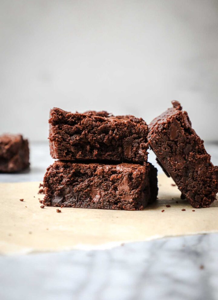 Two double chocolate fudge brownies stacked on top of each other with a third brownie laying at an angle against the two brownies.