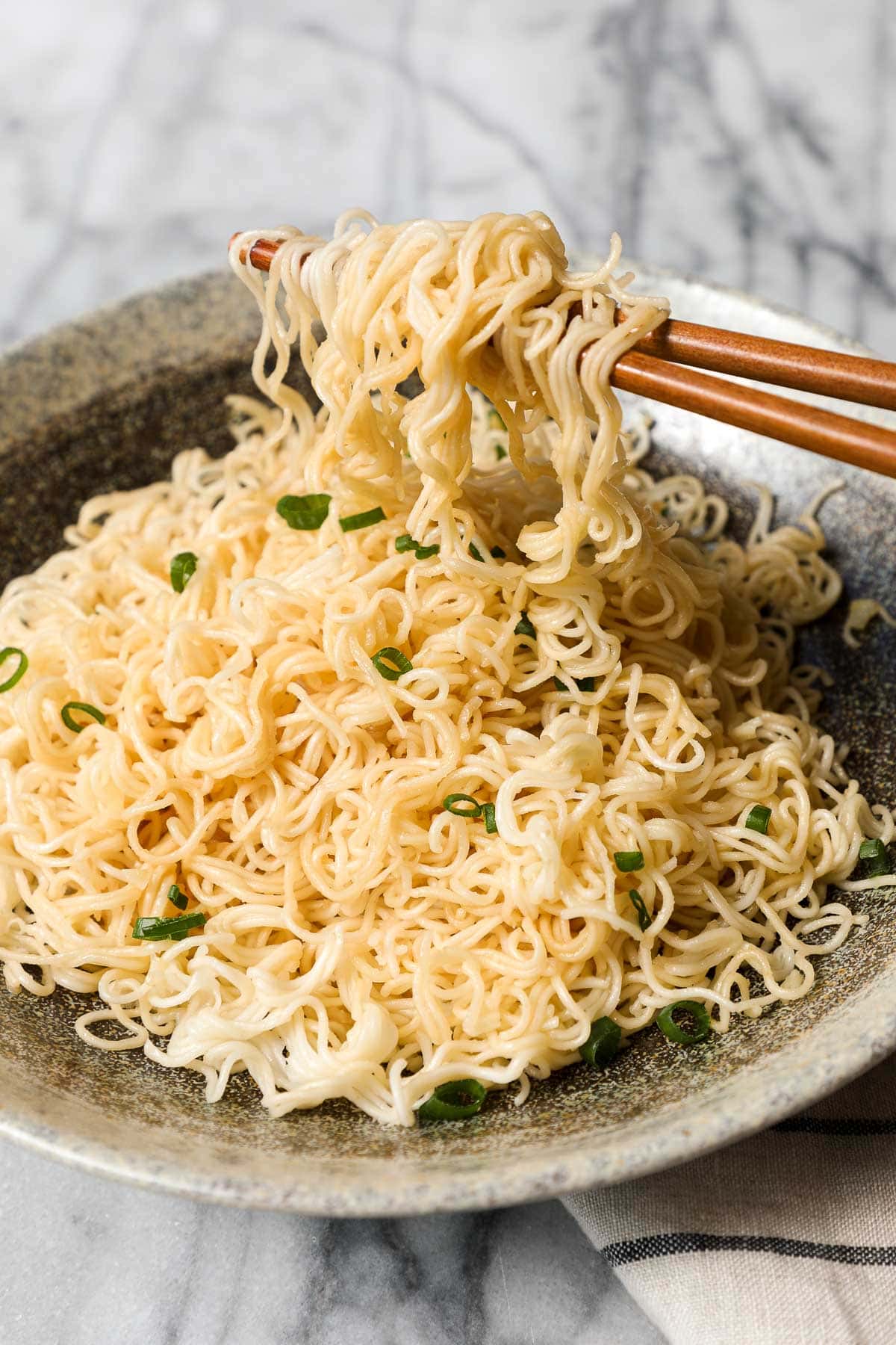 Chopsticks holding up the miso butter noodles over a bowl of noodles.