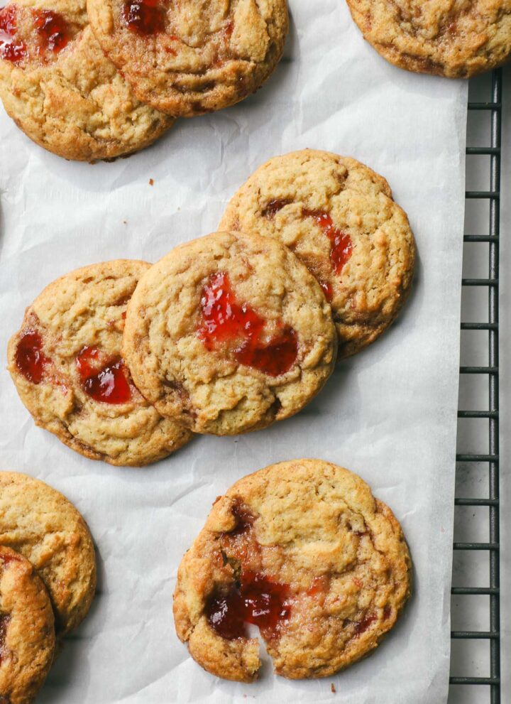 Strawberry Jam Cookies layered on parchment paper on a cookie drying rack.