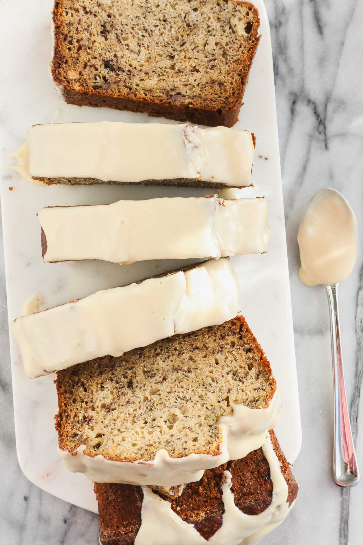 Thick slices of banana bread covered in a white maple glaze on a light background.