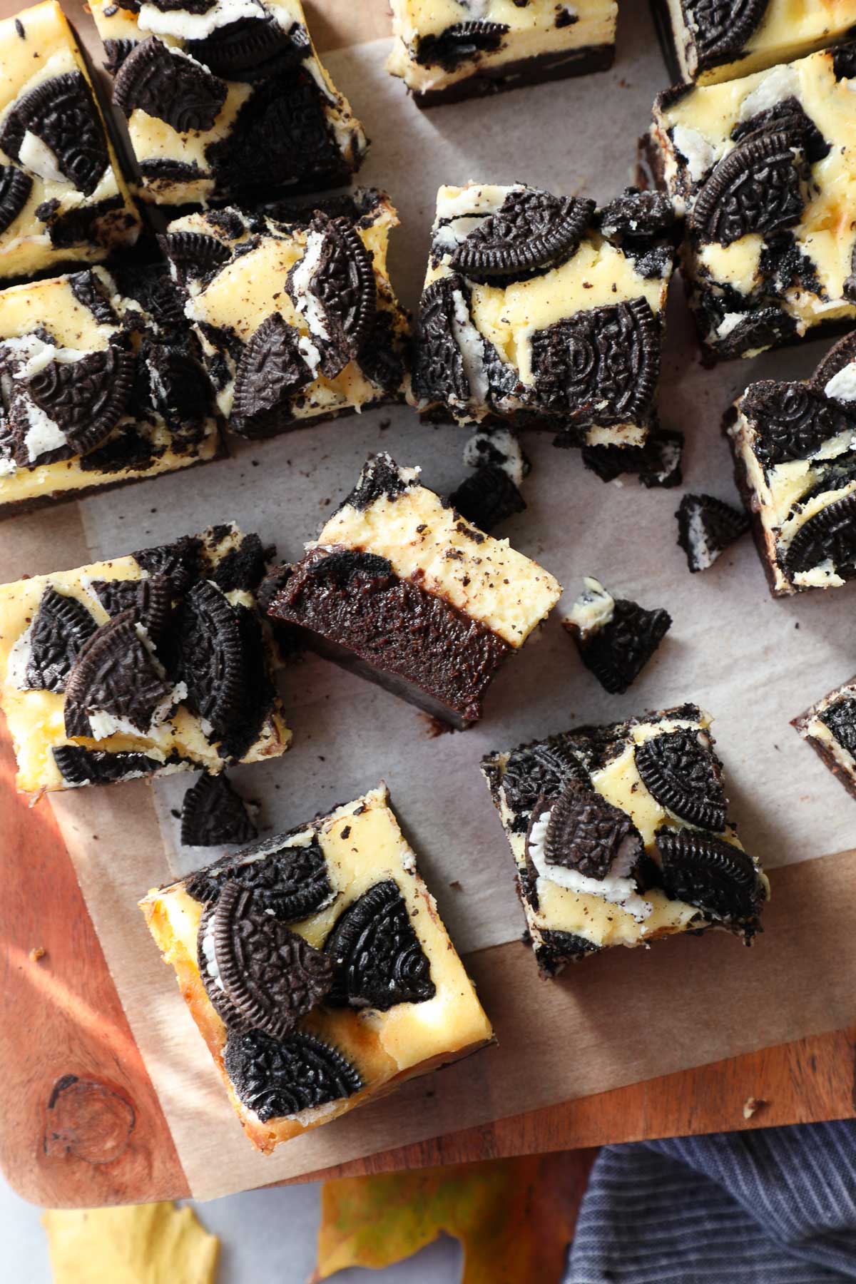 Oreo cheesecake brownies cut into squares on a wooden serving board.