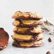 Chocolate Dipped Chocolate Chip Cookies stacked on top of each other showing the bottoms of the cookies dipped in chocolate.