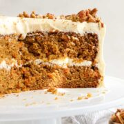 An Olive Oil Carrot Cake with two layers, cream cheese frosting and topped with chopped pecans.