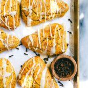Golden Sourdough Pumpkin Scones on a baking sheet drizzled with frosting.