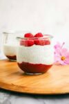 A jar layered with raspberry jam, chia seed pudding, and fresh raspberries.