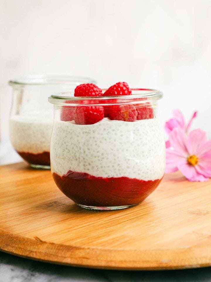 A jar layered with raspberry jam, chia seed pudding, and fresh raspberries.