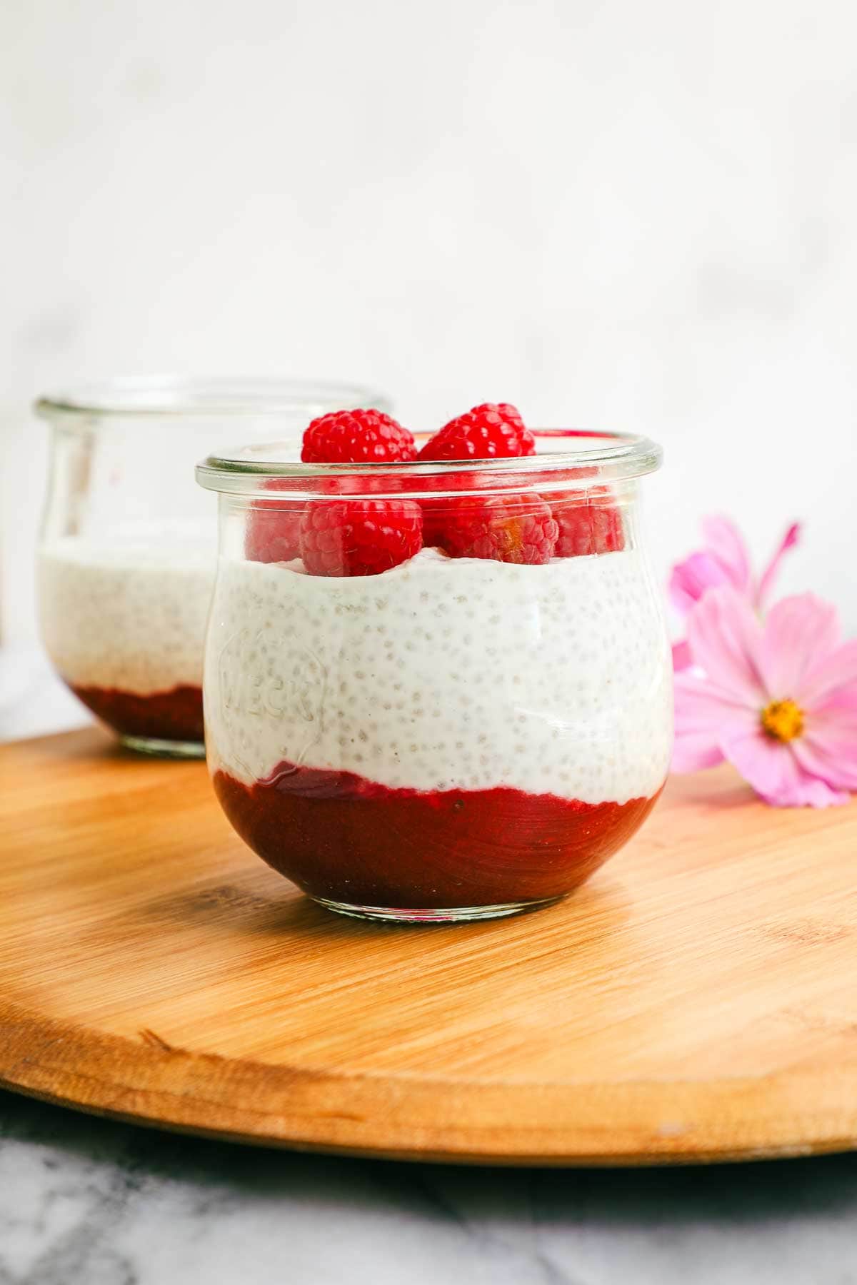 A jar layered with raspberry jam, chia seed pudding, and fresh raspberries.