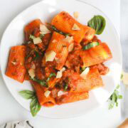A plate of Homemade Cherry Tomato Sauce Pasta with Italian Sausage with parmesan and basil for garnish.