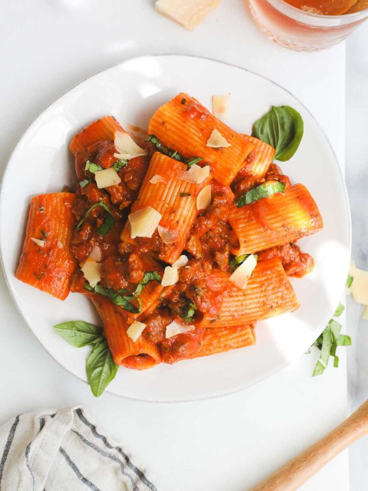 A plate of Homemade Cherry Tomato Sauce Pasta with Italian Sausage with parmesan and basil for garnish.