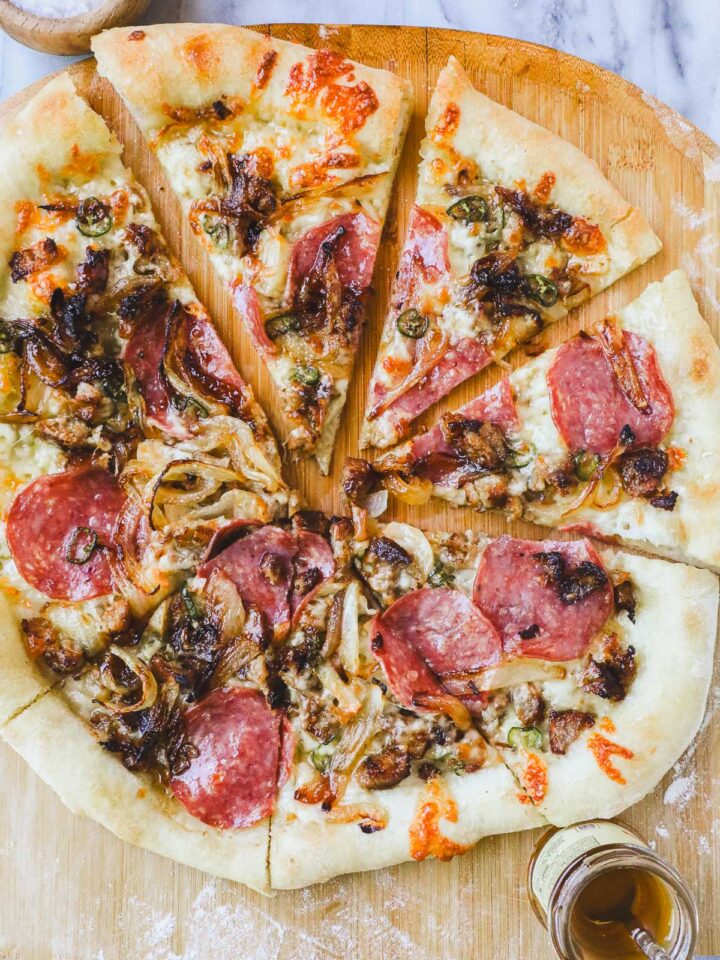Hot Honey Meat Pizza on a pizza peel cut into slices.