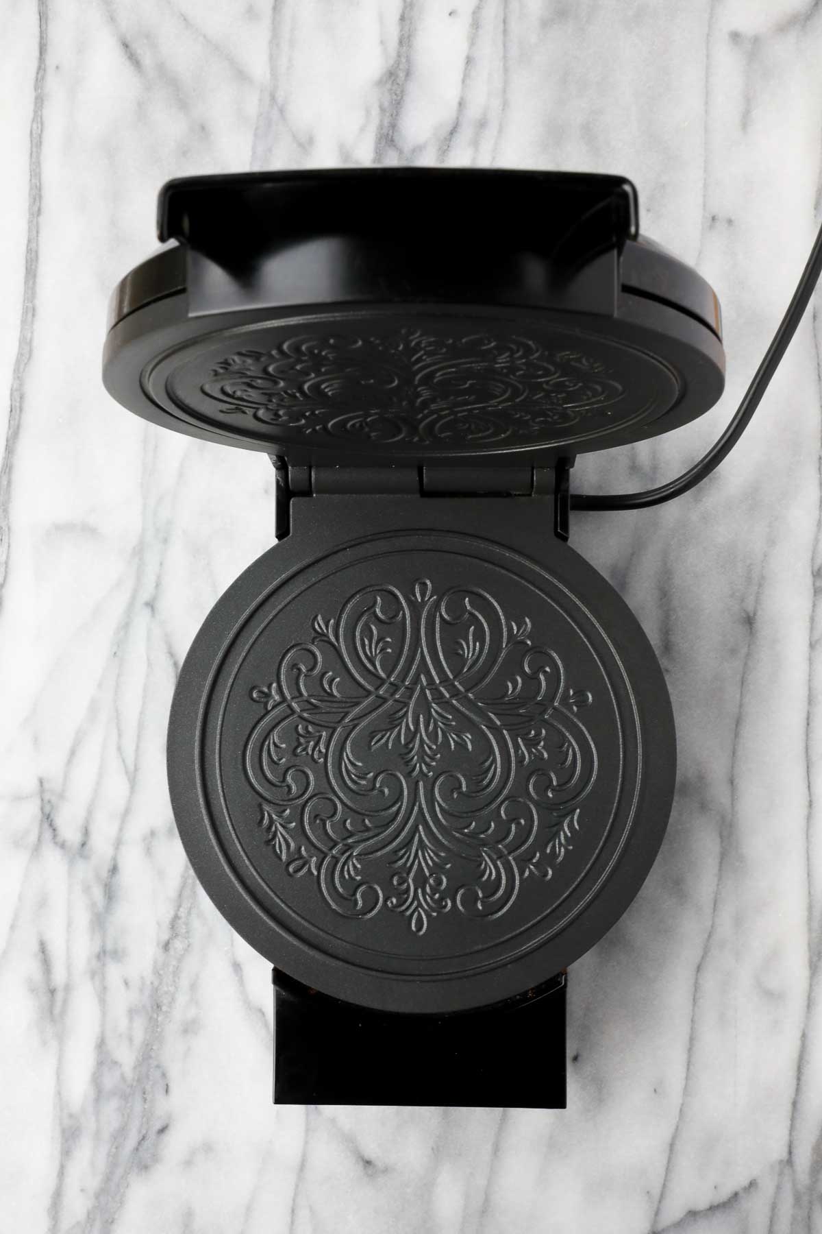 A Krumkake Norwegian Waffle Iron, opened to show the detail of the design inside of the iron, which prints onto the waffles.