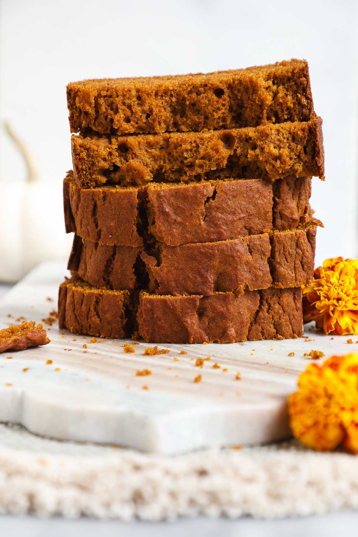 Five slices of Olive Oil Pumpkin Bread stacked vertically on top of each other on a white background.