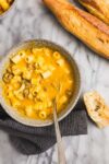 A bowl of vibrant orange Honeynut Squash Soup with Italian Sausage, cauliflower, and ditalini pasta.