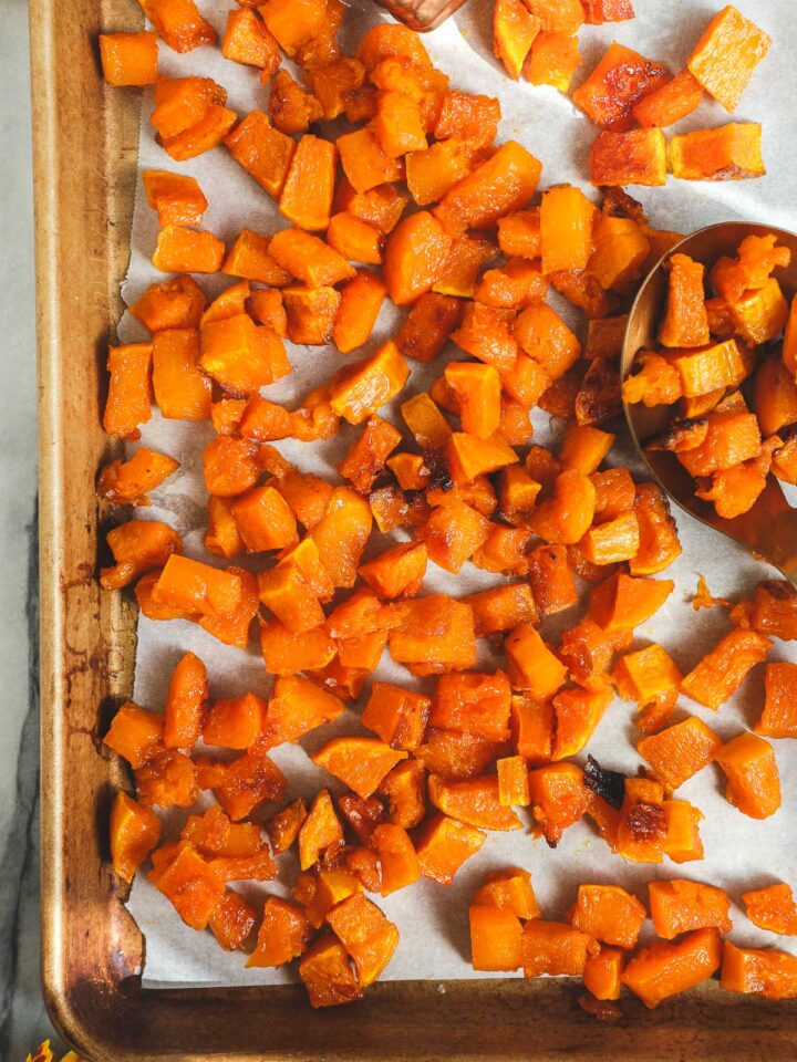 A golden sheet pan with diced and Maple Roasted Butternut Squash.