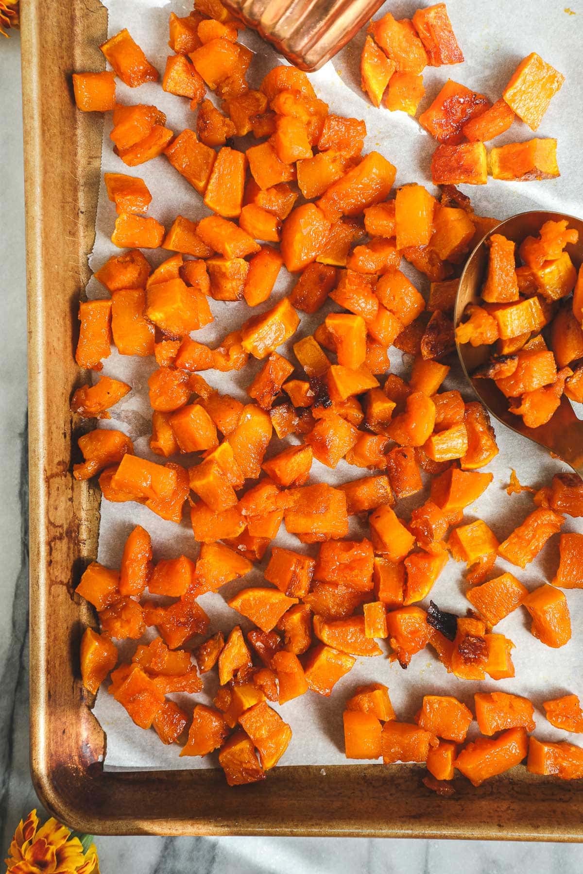 A golden sheet pan with diced and Maple Roasted Butternut Squash.