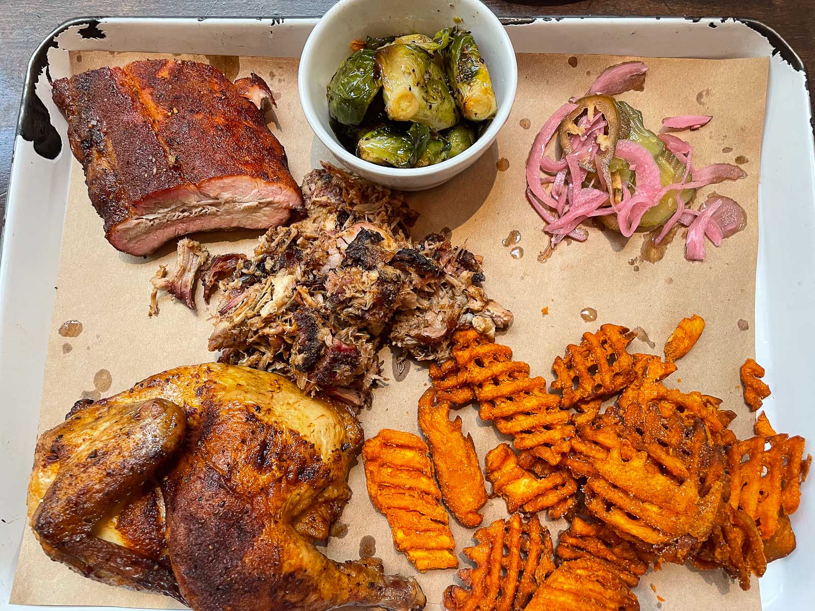A spread of BBQ, roasted pork, ribs, chicken, sweet potato fries, and pickled onions.