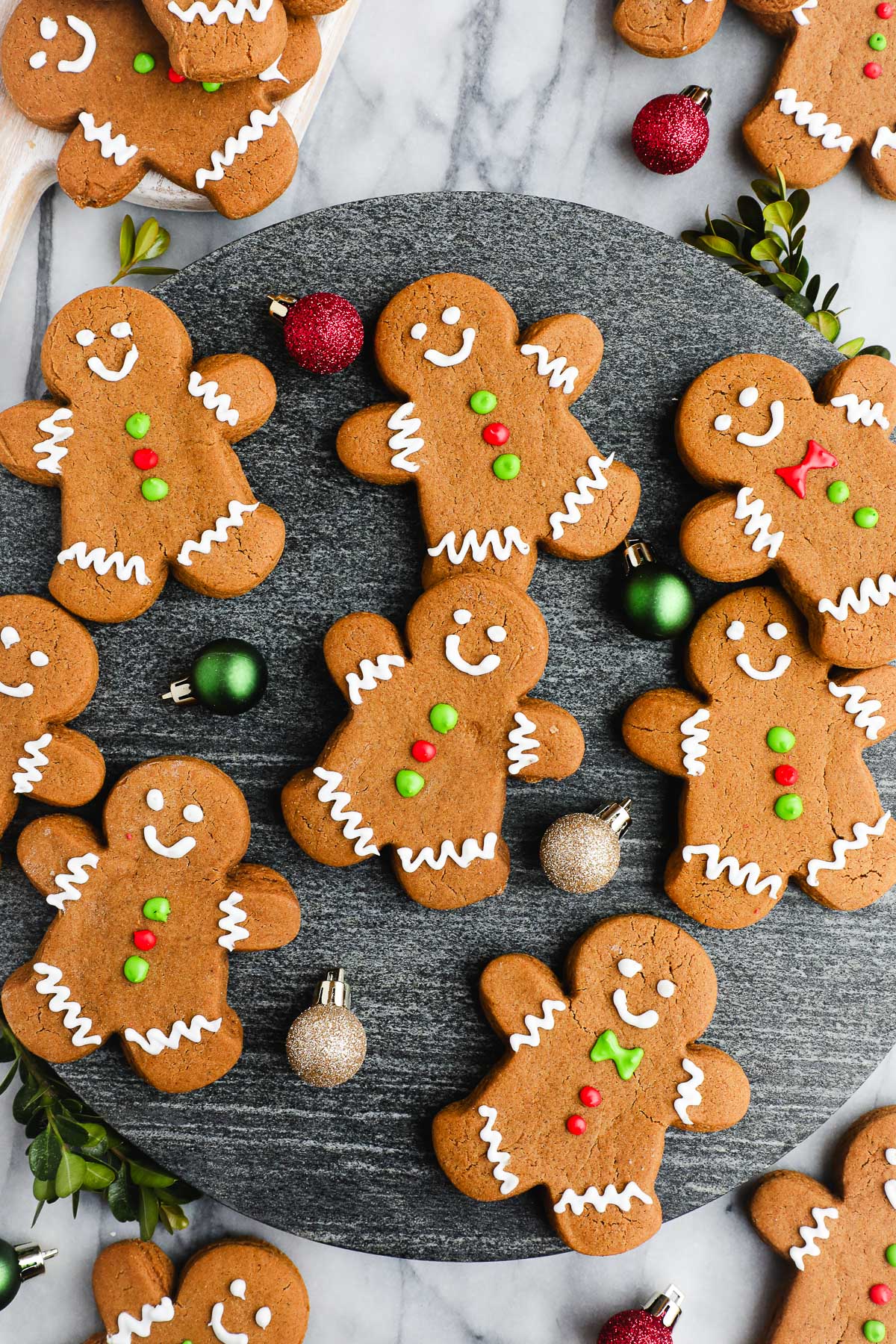 Cut Out Gingerbread cookies decorated with royal icing and colorful icing buttons displayed on a black marble serving dish.
