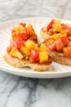 Heirloom Tomato Bruschetta with colorful yellow and red tomatoes diced on a golden toasted slice of baguette with minced basil.