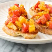 Heirloom Tomato Bruschetta with colorful yellow and red tomatoes diced on a golden toasted slice of baguette with minced basil.