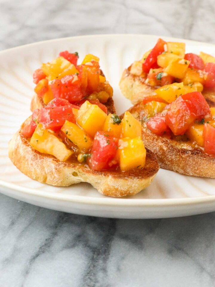 Heirloom Tomato Bruschetta with colorful yellow and red tomatoes diced on a golden toasted slice of baguette with minced basil.
