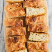 A loaf of golden Bubbly Focaccia cut into many pieces, some turned on their sides to show the bubbly interior.