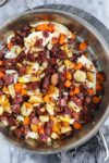 Corned Beef Hash in a large sauté pan with crispy corned beef, crispy potatoes, carrots, and pan fried eggs.