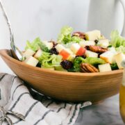 New England Salad in a wooden bowl with romaine lettuce, diced apples, dried cranberries, and pecans.