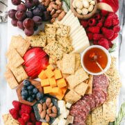 Einkorn crackers on a charcuterie board surrounded by cheese, fruit, salami, and honey.