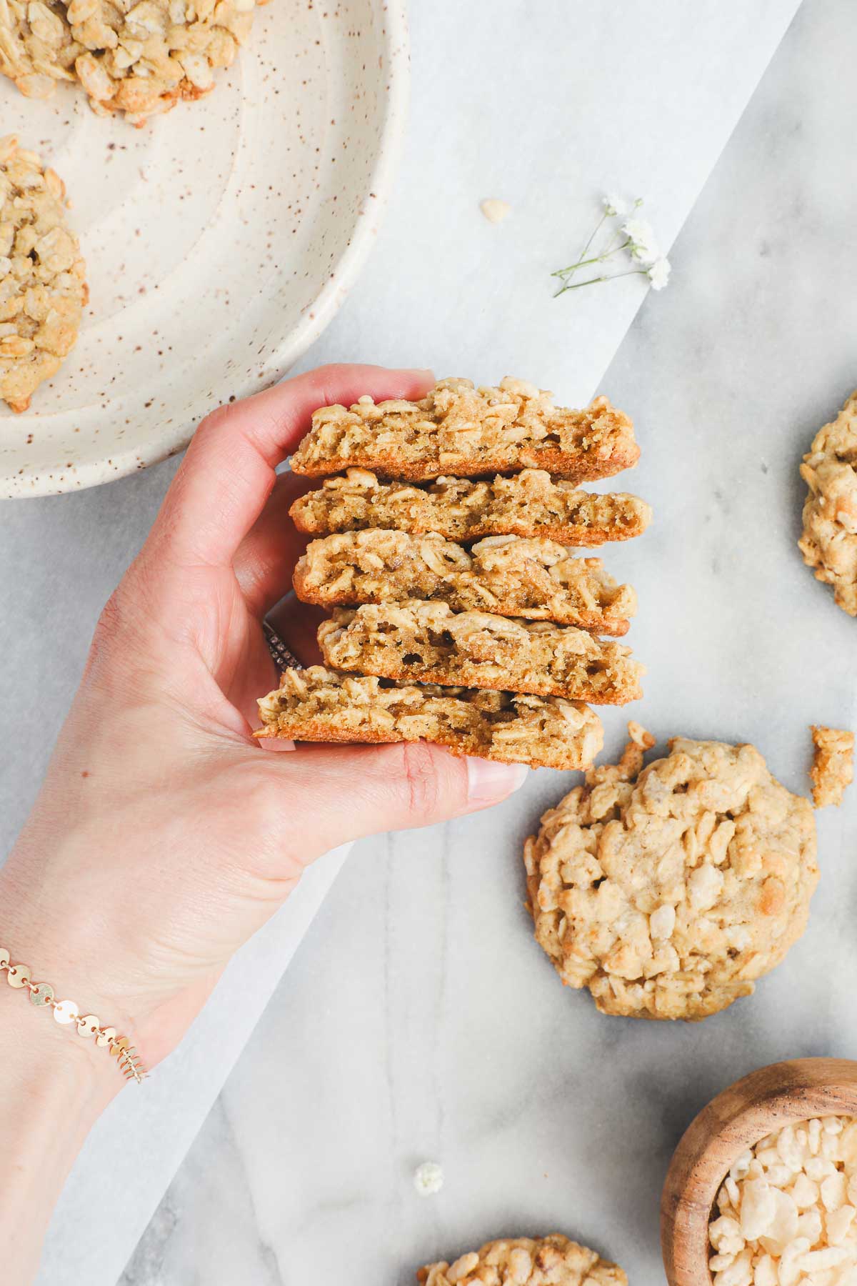 Lauren holding five Oatmeal Rice Krispie Cookies broken in half to show their texture.
