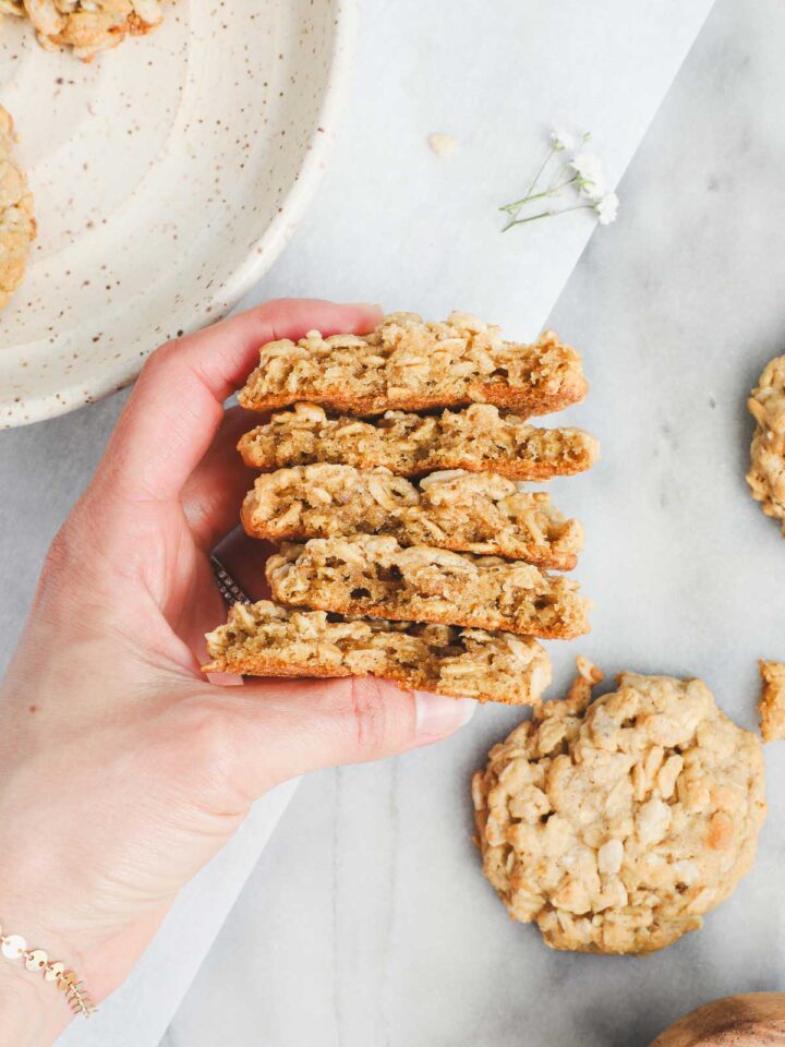 Lauren holding five Oatmeal Rice Krispie Cookies broken in half to show their texture.