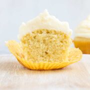 One Olive Oil Cupcake cut in half showing the inside of the cupcake and the tall white frosting.