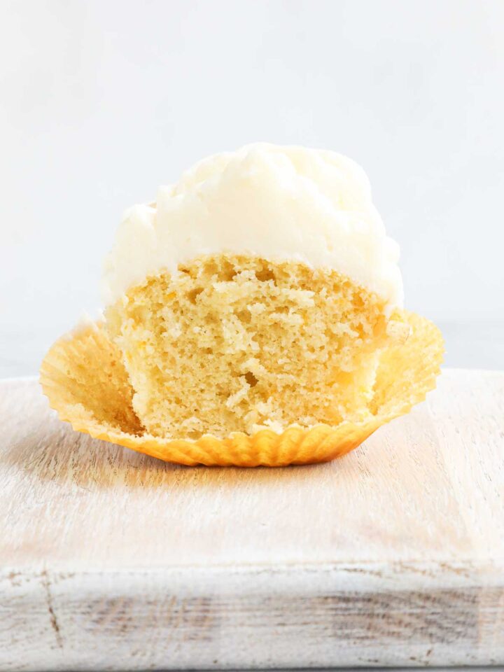 One Olive Oil Cupcake cut in half showing the inside of the cupcake and the tall white frosting.