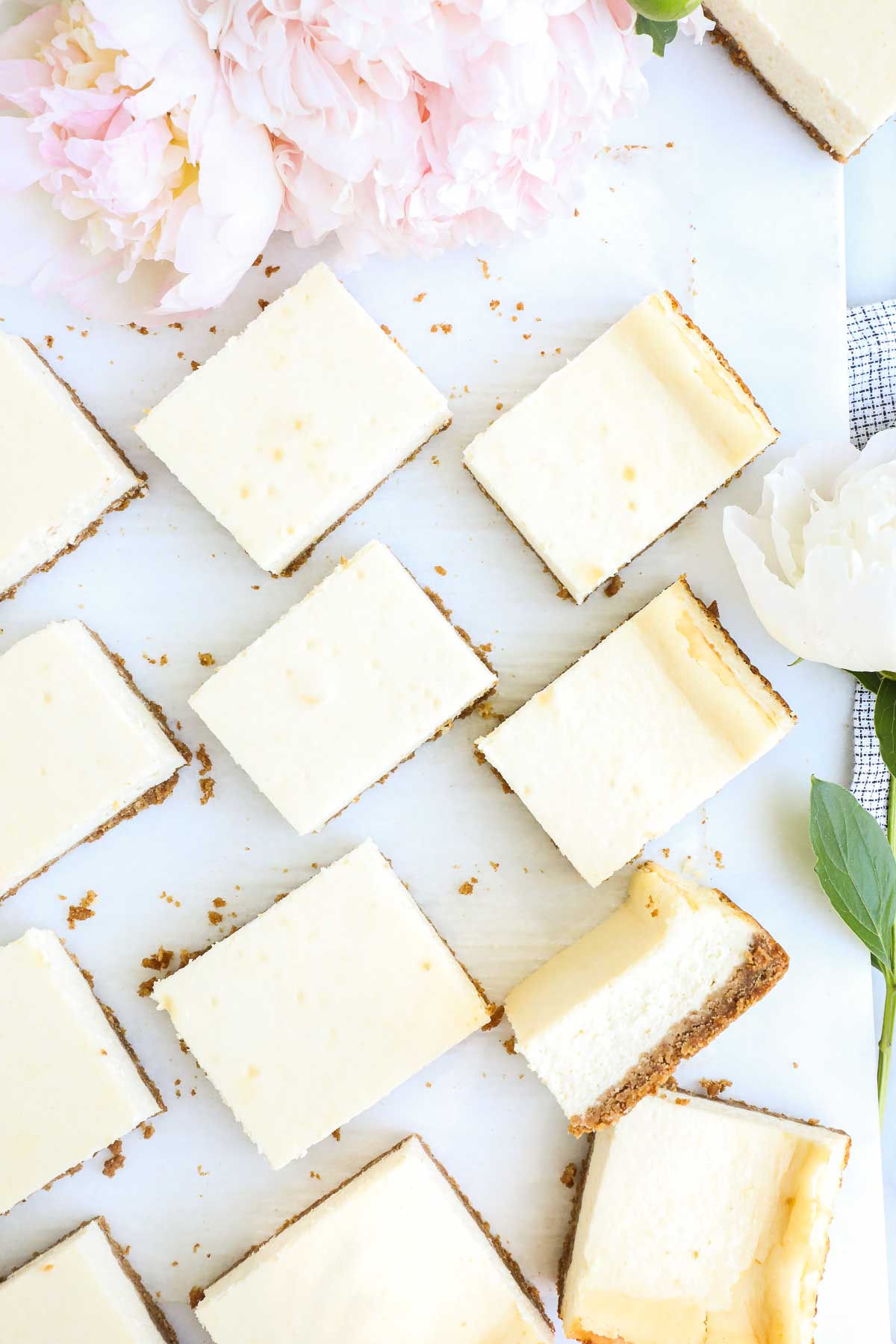 Rectangular slices of Cheesecake in a 9x13 Pan placed on a diagonal on a white background.