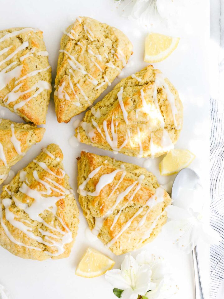Olive Oil Scones arranged in a circle on a white background drizzled with lemon glaze.