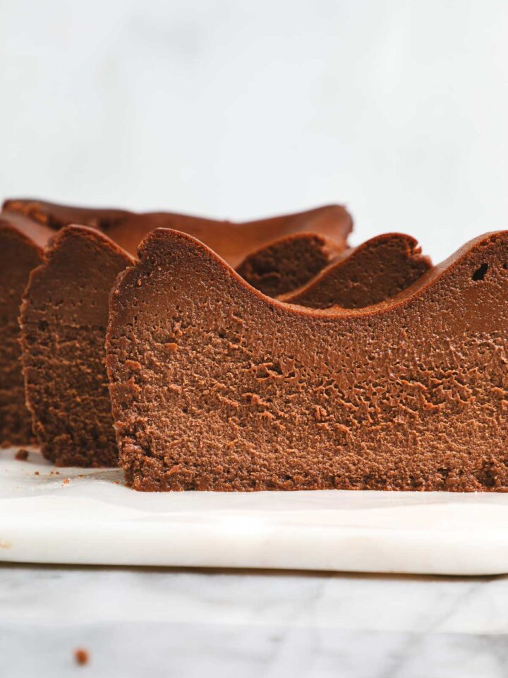 Slices of Chocolate Loaf Basque Cheesecake standing vertically slightly offset from one enough creating a wave pattern.