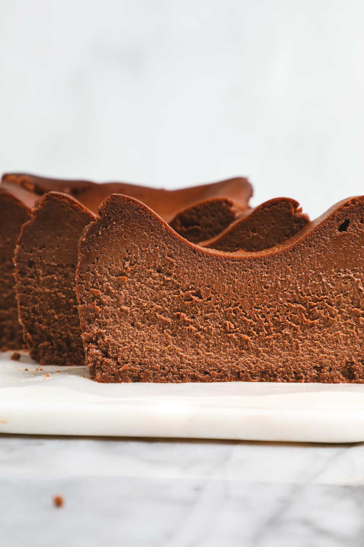 Slices of Chocolate Loaf Basque Cheesecake standing vertically slightly offset from one enough creating a wave pattern.