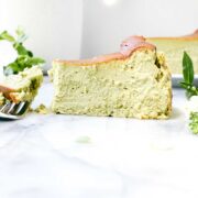A slice of vibrant green Matcha Basque Cheesecake on white marble background with a fork.