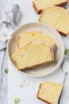 Two slices of Old Fashioned Lemon Pound Cake with lemon glaze on a small dessert plate on a white background.