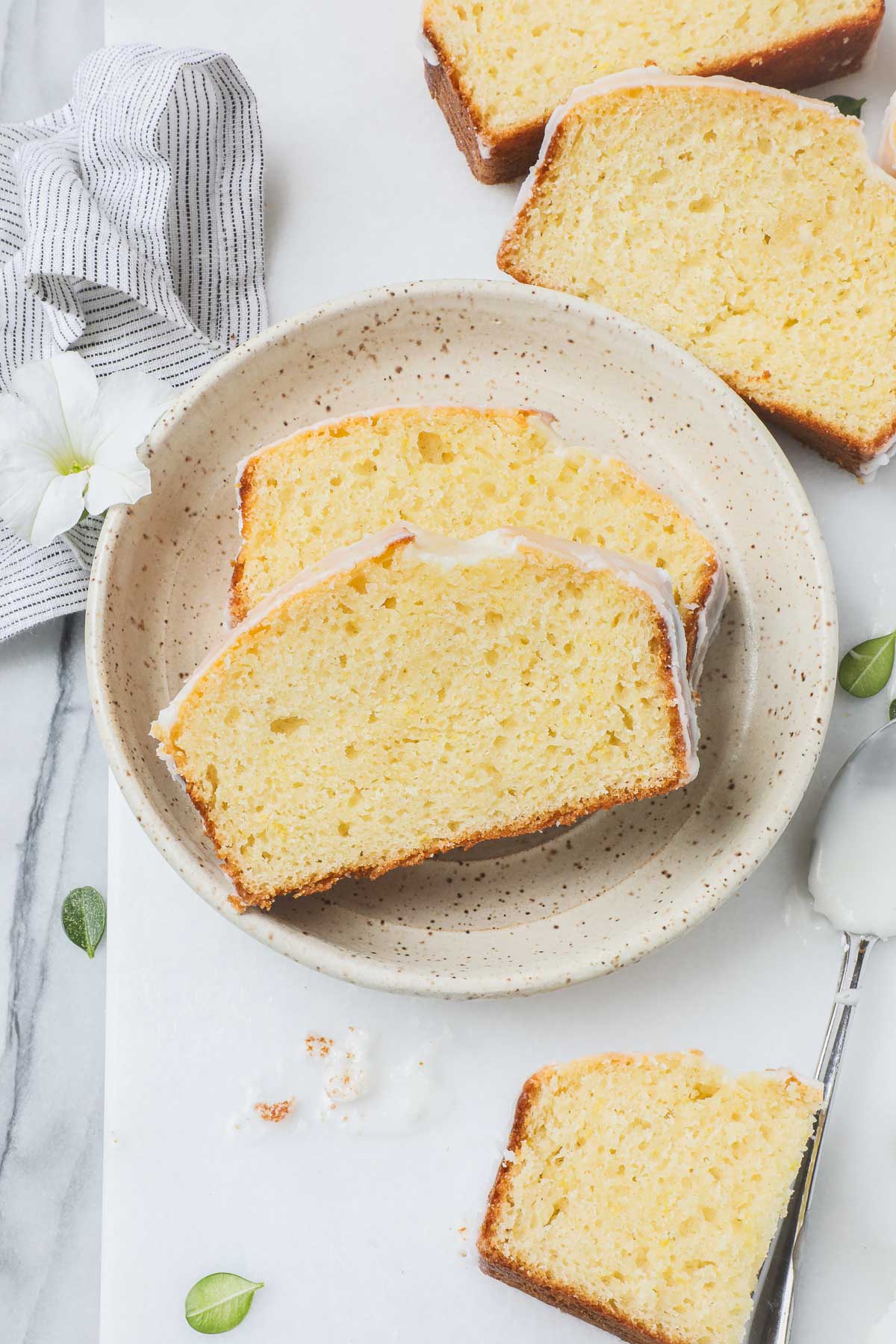 Two slices of Old Fashioned Lemon Pound Cake with lemon glaze on a small dessert plate on a white background.
