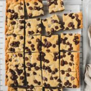 Chocolate Chip Cookie Bars removed from a 9x13 pan and cut into 24 squares laying flat on parchment paper on a cookie drying rack.